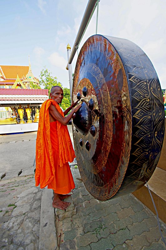 Тайский монах извлекает звуки из большого ритуального гонга. Тайланд, о. Пхукет. - Евгений Васин