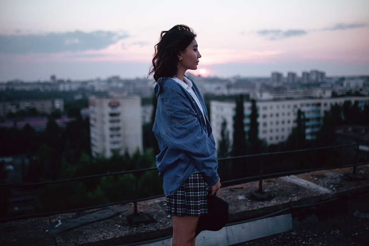 Девушка в шляпе и джинсовой куртке стоит на крыше на фоне вечерней Уфы - Lenar Abdrakhmanov