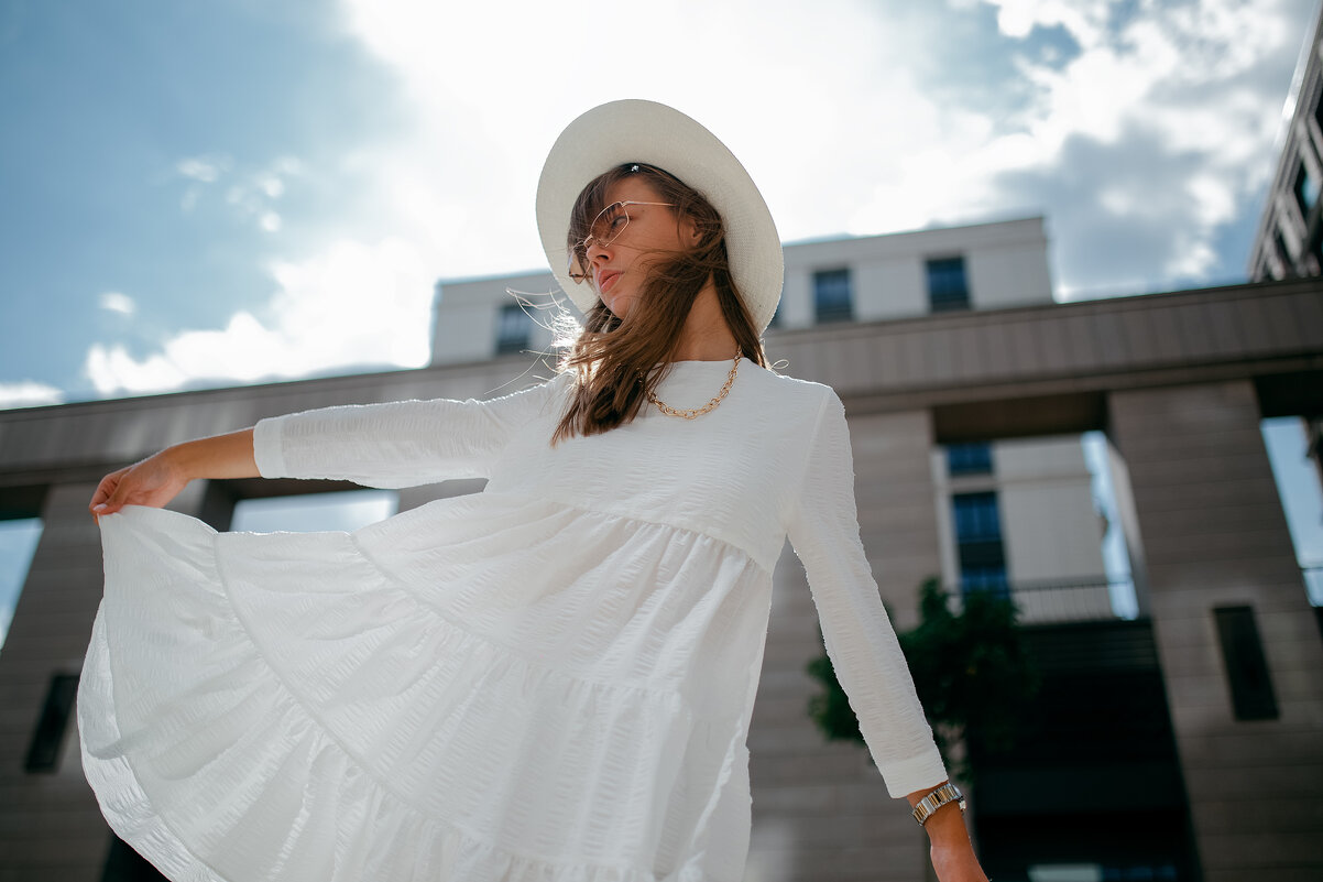 Девушка в белом платье и белой шляпе в центре города во время сильного ветра - Lenar Abdrakhmanov