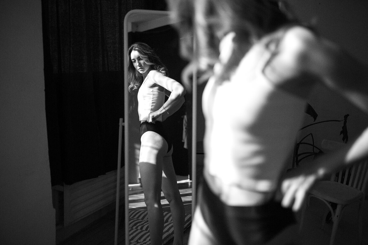 Девушка в белом топе и черном белье смотрит на себя в зеркало в солнечный день - Lenar Abdrakhmanov