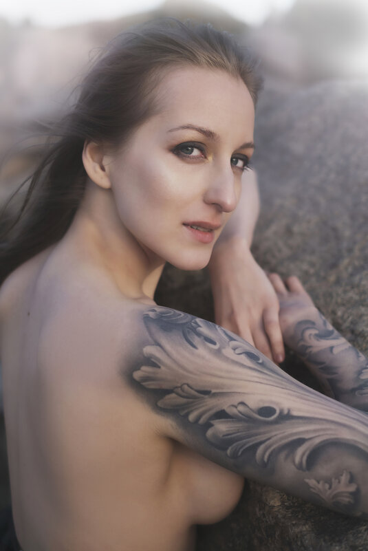 Красивая девушка с татуировкой возле скал на берегу - Кирилл Селезнев