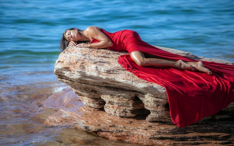 девушка-в-красном-платье-лежит-на-камне-у-моря