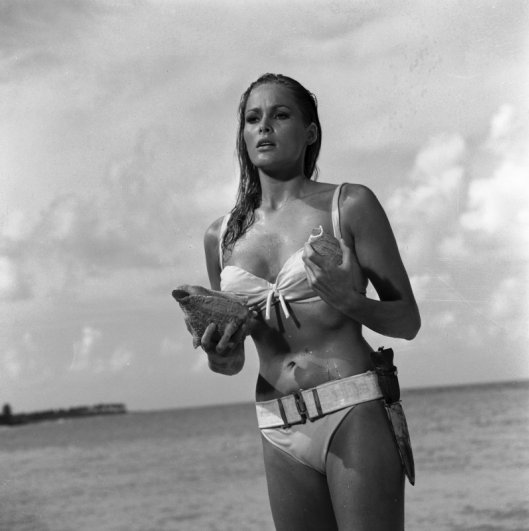 Emerging from the sea singing calypso 'Under the Mango Tree' Honey (Ursula Andress) is surprised to hear someone taking up the song refrain. Copyright Notice - © 1962 Danjaq, LLC and United Artists Corporation. All rights reserved.